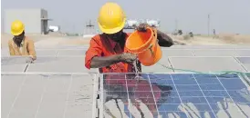  ?? SAM PANTHAKY/AFP/GETTY IMAGES/FILES ?? A worker washes dust off solar panels near India’s Narmada Canal. Brookfield Asset Management is making a major foray into solar power.