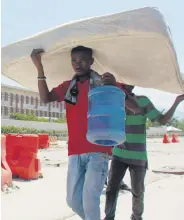  ?? ?? Two people carry a mattress as they walk past the U.S. Embassy in Port-au-Prince, Haiti, March 12, 2024.