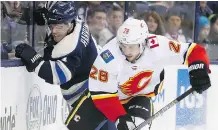  ??  ?? The Blue Jackets’ Scott Harrington, left, and the Flames’ Elias Lindholm fight for a loose puck during Tuesday night’s contest.