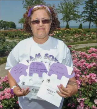  ?? ERIC BONZAR — THE MORNING JOURNAL ?? Lorain resident Sylvia Soto Brown holds Alzheimer awareness luminaries while standing in Lorain County Metro Parks’ Lakeview Park Rose Garden on June 14. On June 21, the Alzheimer’s Associatio­n Cleveland Area Chapter volunteer will host a luminary...