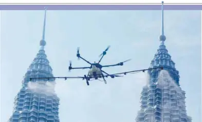  ??  ?? SPRAYING FROM ABOVE .... A drone, with a 16-litre capacity, being used to disinfect tall buildings in Kuala Lumpur. – ZAHID IZZANI/THESUN
