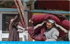  ?? —AFP ?? KABUL, Afghanista­n: Workers carry carpets on their shoulders at Chicken Street in Kabul yesterday.