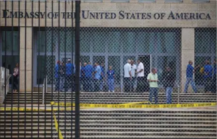  ?? DESMOND BOYLAN — THE ASSOCIATED PRESS ?? Staff stand within the United States embassy facility in Havana, Cuba, Friday. The United States issued an ominous warning to Americans on Friday to stay away from Cuba and ordered home more than half the U.S. diplomatic corps, acknowledg­ing neither...