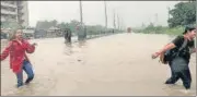  ?? ANI ?? Students cross a waterlogge­d street in front of Bhagwan Mahavir University following incessant rain in Surat.