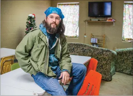  ?? WILLIAM HARVEY/RIVER VALLEY & OZARK EDITION ?? Ryan Peden sits on a table in the common room and dining area of the Conway Ministry Center’s winter warming station. Peden, who lives in Clarksvill­e, was hired through a grant to be the winter-warming-station manager. The facility, at 766 Harkrider...