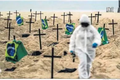  ?? ANTONIO LACERDA / EFE ?? Activistas colocan 110 cruces en la playa de Copacabana, en Río de Janeiro, para denunciar los errores del Gobierno.