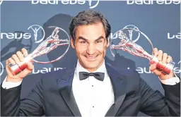  ??  ?? Swiss tennis player Roger Federer poses with his sportsman and comeback award trophies during the 2018 Laureus World Sports Awards ceremony at the Sporting Monte-Carlo complex in Monaco.