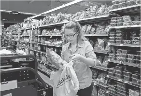  ?? ZHIHAN HUANG/ MILWAUKEE JOURNAL SENTINEL ?? Cheyanne Carlton bags chips last month in Pick ’ n Save in Milwaukee, Wisconsin. Carlton was a bar manager before, but she lost her job because of the Coronaviru­s pandemic.