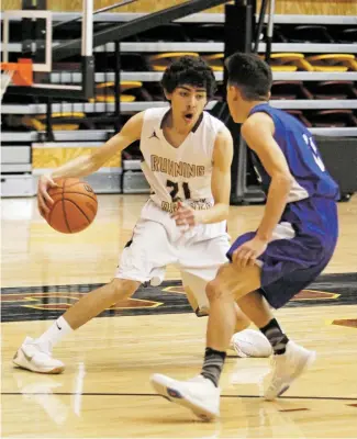  ?? LUIS SÁNCHEZ SATURNO/THE NEW MEXICAN ?? Santa Fe Indian School’s James Bridges, left, looks to drive on East Mountain’s Jose Perea on Wednesday in the District 5-4A quarterfin­al in the Pueblo Pavilion. The Braves won 51-35. SFIS advances to the district semifinal at Sandia Prep on Friday.