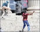  ??  ?? A demonstrat­or hurls rocks at security guards at Wits.