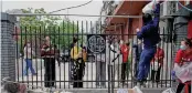  ?? AFP ?? A delivery worker passes items over a fence to people in a residentia­l area under lockdown due to Covid-19 curbs in Beijing on Monday. —