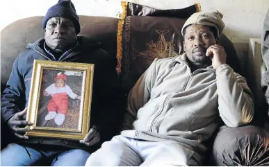  ??  ?? Neighbour Jan Khuthedi tries to comfort Tom Mokone, who holds a portrait of her granddaugh­ter Mpopo Mafoko, who lost her life during a shack fire on Saturday.