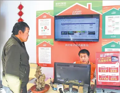  ?? DU YU / XINHUA ?? Liu Yan (right) uses the internet to book train tickets for locals at a village in Zhaomiao town in Fuyang, Anhui province.