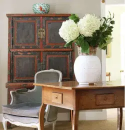  ??  ?? ABOVE The pentagonal oak table is early 20th-century English, from Foster & Gane. Atop it sits a 1960s Swedish ceramic and rattan vase filled with hydrangeas. The 18th-century bergère is in its original paint.