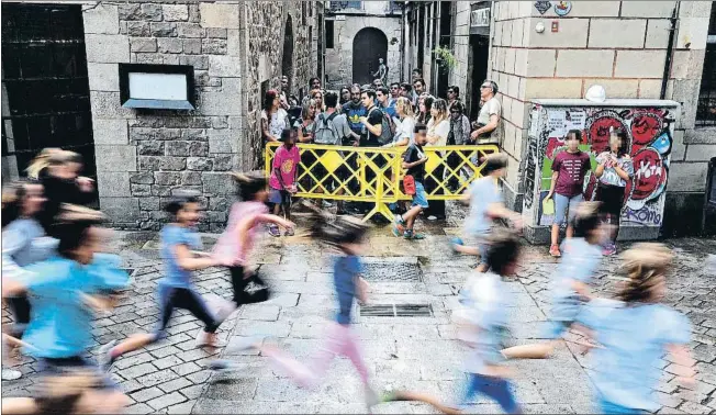  ?? ÀLEX GARCIA ?? Tras la valla. Un guía explica a un grupo de turistas que no pueden entrar en la plaza para que los niños de Sant Felip Neri disfruten de su rato de asueto