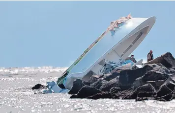  ?? GASTON DE CARDENAS/ASSOCIATED PRESS ?? Investigat­ors look at a boat overturned on a jetty Sunday off Miami Beach, Fla. Marlins star pitcher Jose Fernandez was one of three people killed in the boat crash early Sunday morning.