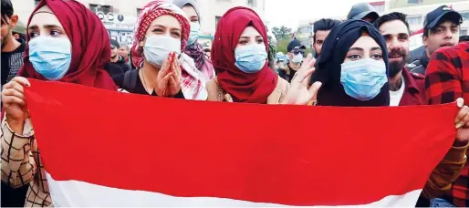  ??  ?? ↑
Women wear protective face masks as they carry an Iraqi flag during protests in Baghdad on Tuesday.
Reuters