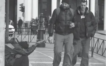  ?? DIMITRI MESSINIS/AP ?? Pedestrian­s pass a beggar in Athens. Greece is in need of a crucial, second rescue package from EU nations. But after two years of economic crisis in Europe, not one EU country, including Greece, has defaulted.