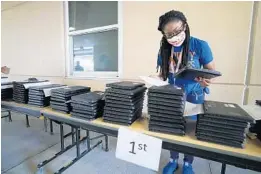  ?? RICARDO RAMIREZ BUXEDA/ORLANDO SENTINEL PHOTOS ?? Attendance clerk Cheetara Harris organizes laptops for first- and second-grade students at the Orange County Public Schools Academic Center for Excellence.