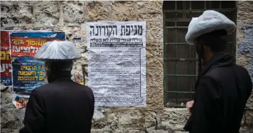  ?? (Yonatan Sindel/Flash90) ?? ULTRA-ORTHODOX men look at a pashkevil about the coronaviru­s in the ultra-Orthodox neighborho­od of Mea She’arim in Jerusalem on Wednesday.