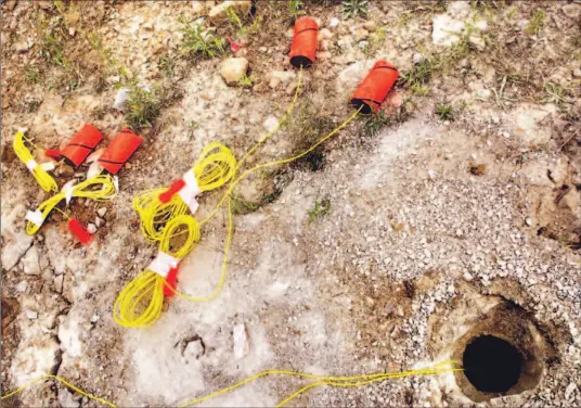  ?? JIM ROSS/TORONTO STAR ?? Big rock to smaller rock begins with a bang. A detonator lays on the ground, above, waiting to be put in the hole at right where the explosives will be set off to loosen a rock face at the Lafarge quarry in Dundas. Below, the quarry and the blast;...