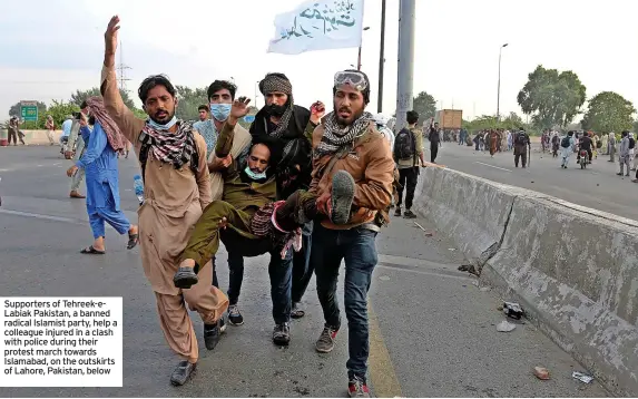 ?? ?? Supporters of Tehreek-eLabiak Pakistan, a banned radical Islamist party, help a colleague injured in a clash with police during their protest march towards Islamabad, on the outskirts of Lahore, Pakistan, below