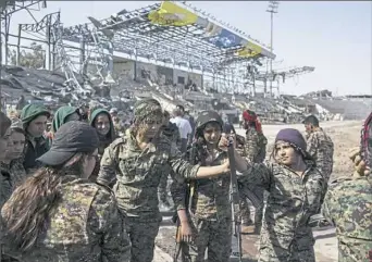  ?? Asmaa Waguih/Associated Press ?? Members of the U.S.-backed Syrian Democratic Forces celebrate at stadium that was the site of Islamic State fighters’ last stand in the city of Raqqa, Syria. The SDF on Sunday reported the capture of Syria’s largest oil field from IS in neighborin­g...