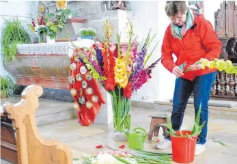  ?? FOTO: EVA WINKHART ?? Gertrud Auchter steckt den großen Gladiolens­trauß in der Kirche neben dem Martinsman­tel.