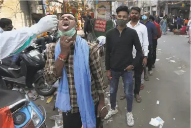  ?? Manish Swarup / Associated Press ?? A health worker tests for COVID19 at a market area in New Delhi. The disease is on the rise in India’s capital, and authoritie­s found the prevalence of infections in markets was higher than expected.