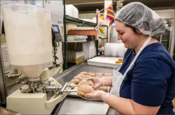  ?? Lucy Schaly/Post-Gazette ?? Liz Barilla, front production manager at Bethel Bakery, fills two fresh, deep-fried paczki with buttercrea­m frosting on Monday.