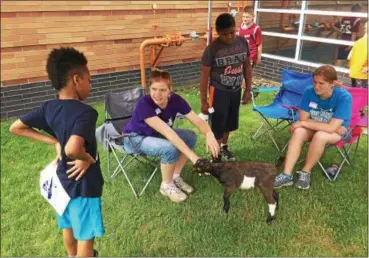  ?? CHAD FELTON — THE NEWS-HERALD ?? CloverWish­es Family Farm members Michaela, left, and Colleen Darby, introduce Porkchop, a Lamancha dairy goat, to Perry Elementary School students during Lake County’s first Youth Ag Day on May 31. The event allows all elementary school students to...