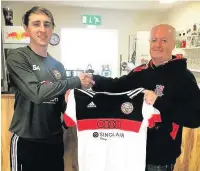  ??  ?? Porthcawl Town import Adam Jones receives a training shirt from club chairman Alex Walker