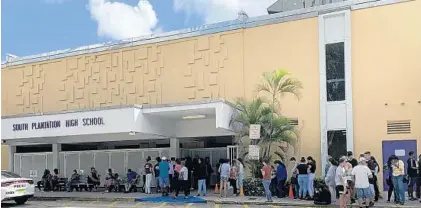  ?? SCOTT TRAVIS/SOUTH FLORIDA SUN SENTINEL ?? A line forms Friday at South Plantation High School as students and parents pick up laptops that students will need to switch to online learning because of the coronaviru­s pandemic.