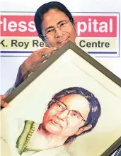  ?? — PTI ?? West Bengal chief minister Mamata Banerjee receives a painting of her during a round-table conference in Kolkata on Wednesday.