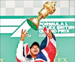  ?? ANDREJ ISAKOVIC/AFP ?? Mercedes’ British driver Lewis Hamilton throws the trophy into the air after the British F1 Grand Prix at the Silverston­e motor racing circuit on July 14.