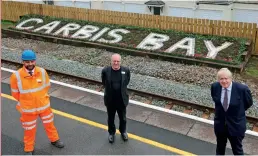  ?? (Network Rail) ?? PM Boris Johnson (right) joins Network Rail CEO Sir Peter Hendy (centre) in front of the rejuvenate­d station sign at Carbis Bay.