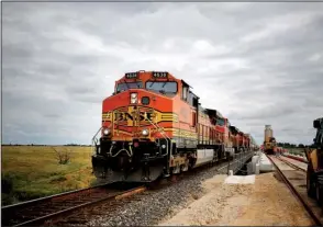  ?? Bloomberg News/LUKE SHARRETT ?? A train passes by workers constructi­ng a BNSF Railway line in Alva, Okla., in 2015. The company is one of several railways that are fighting an effort by oil refiners to shed the responsibi­lity of proving compliance with a biofuel rule, a process they...
