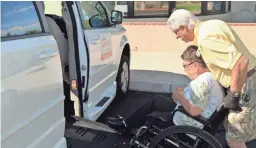  ??  ?? Rich Greene, a volunteer with Northwest Valley Connect, helps a senior passenger board a vehicle.