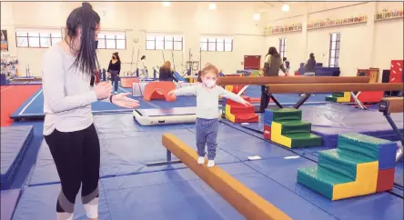  ?? Ned Gerard / Hearst Connecticu­t Media ?? Eliza Carey walks on a balance beam in the company of her au pair, Bernelee Kritzinger, during a visit to the gymnasium of the Westport Weston Family YMCA in Westport on Tuesday.