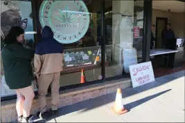  ?? SONIA WARAICH — THE TIMES-STANDARD ?? Customers practice social distancing while they browse cannabis at retail dispensary Proper Wellness Center in Eureka on Friday afternoon. Dispensari­es said they’ve seen a surge in customers over the past week ahead of a shelter in place order issued by the county health officer Thursday to curb the spread of COVID-19.