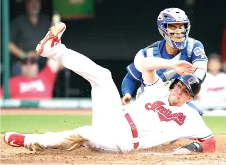  ?? Tony Dejak/Associated Press ?? ■ Cleveland Indians' Bradley Zimmer slides safely into home plate as Texas Rangers catcher Robinson Chirinos is late on the tag in the fifth inning of a baseball game Monday in Cleveland.
