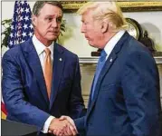  ?? ZACH GIBSON /POOL / TNS ?? U.S. Sen. David Perdue, R-Ga., shakes hands with President Donald Trump recently. Perdue, who rarely breaks ranks with Trump, is urging him to change direction on his tariff proposal.