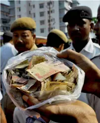  ??  ?? Police show the torn notes of Rs500 and Rs1000 recovered from a drain at Bhetapara in Guwahati, Assam, on Monday. —