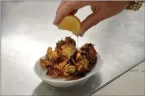  ?? ?? A Meyer lemon is squeezed over Roman-style fried artichokes at the restaurant Chez Noir in Carmel-By-The-Sea on May 23. Chez Noir uses artichokes grown by Pezzini Farms exclusivel­y.