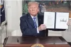  ?? EVAN VUCCI/AP ?? President Donald Trump holds up an order he signed at the White House Tuesday that reinstates sanctions on Iran.