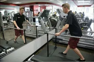  ?? Assoicated Press ?? Aaron Baker, right, a former motocross racer who was paralyzed from the neck down in a crash while practicing on a track in 1999, walks on a treadmill May 5 at the Center of Restorativ­e Exercise in the Northridge section of Los Angeles.