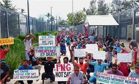  ?? — AP ?? Holding ground: Asylum seekers holding up banners protesting their relocation to less well-guarded centres at the Manus Island immigratio­n detention centre in Papua New Guinea