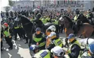  ?? AP PHOTO/ALBERTO PEZZALI ?? A wounded member of a far-right group is escorted by British police officers in riot gear, during scuffles as police tries to contain a protest at Trafalgar Square in central London on Saturday.