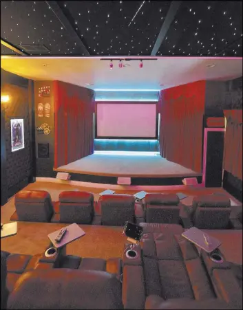  ??  ?? The theater walls are red velvet-tufted fabric, and one wall features faux leather paper. LED lights in the ceiling mimic stars.