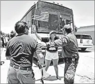  ?? DAVID J. PHILLIP/AP ?? A Border Patrol agent tries to move protesters from blocking a bus carrying immigrant children outside a processing center Saturday in McAllen, Texas. The bus eventually left.